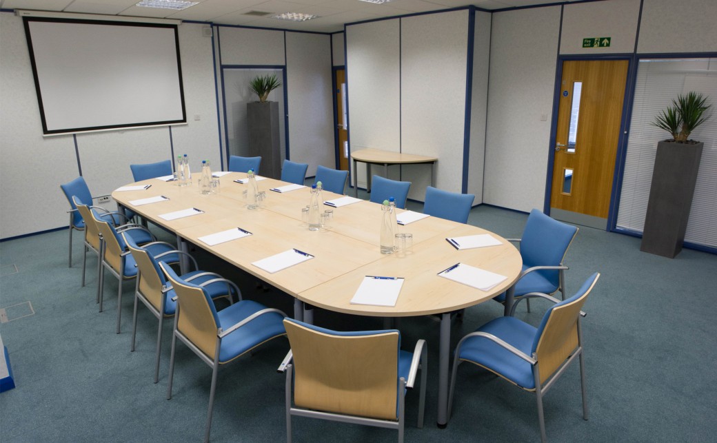 Shot of Garda room in boardroom layout with projector screen at the back at The Ark Conference Centre in Basingstoke Hampshire